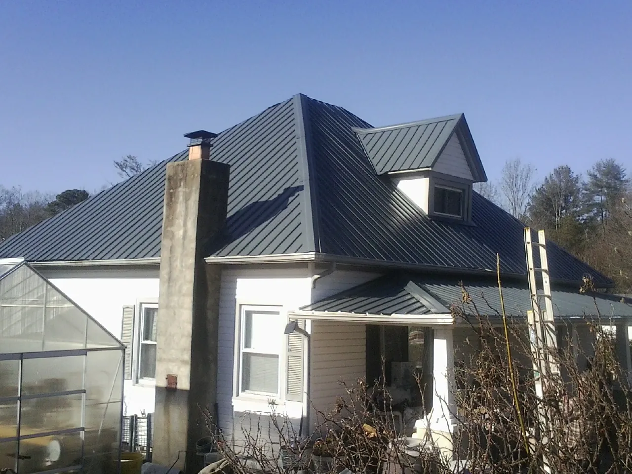 Dark blue standing seam metal roof on a white farmhouse with dormer — Slate & Tile Roof Repair by Roofing Brothers in Bloomsbury