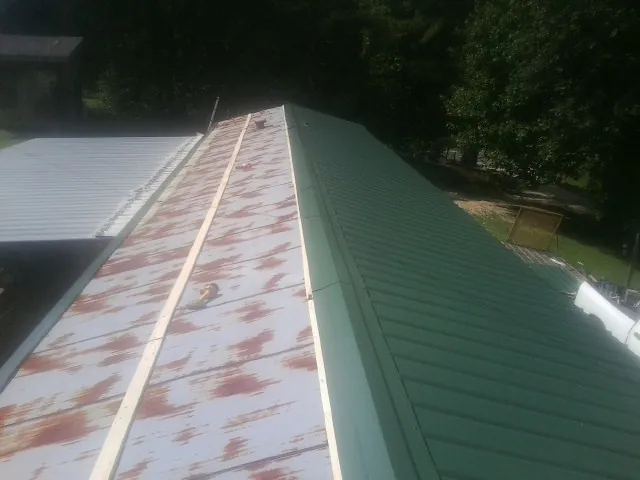Old rusted panels beside newly installed green metal roofing — Wind Damage Roof Repair by Roofing Brothers in Bloomsbury