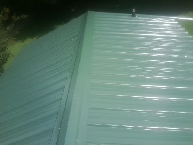New green metal panels meeting at the ridge of a roof — Flat Roof Repair work by our crew in Bloomsbury