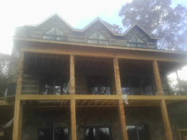 Dormers and porch framing on a large log home under construction — Roof Coating work by our crew in Bloomsbury