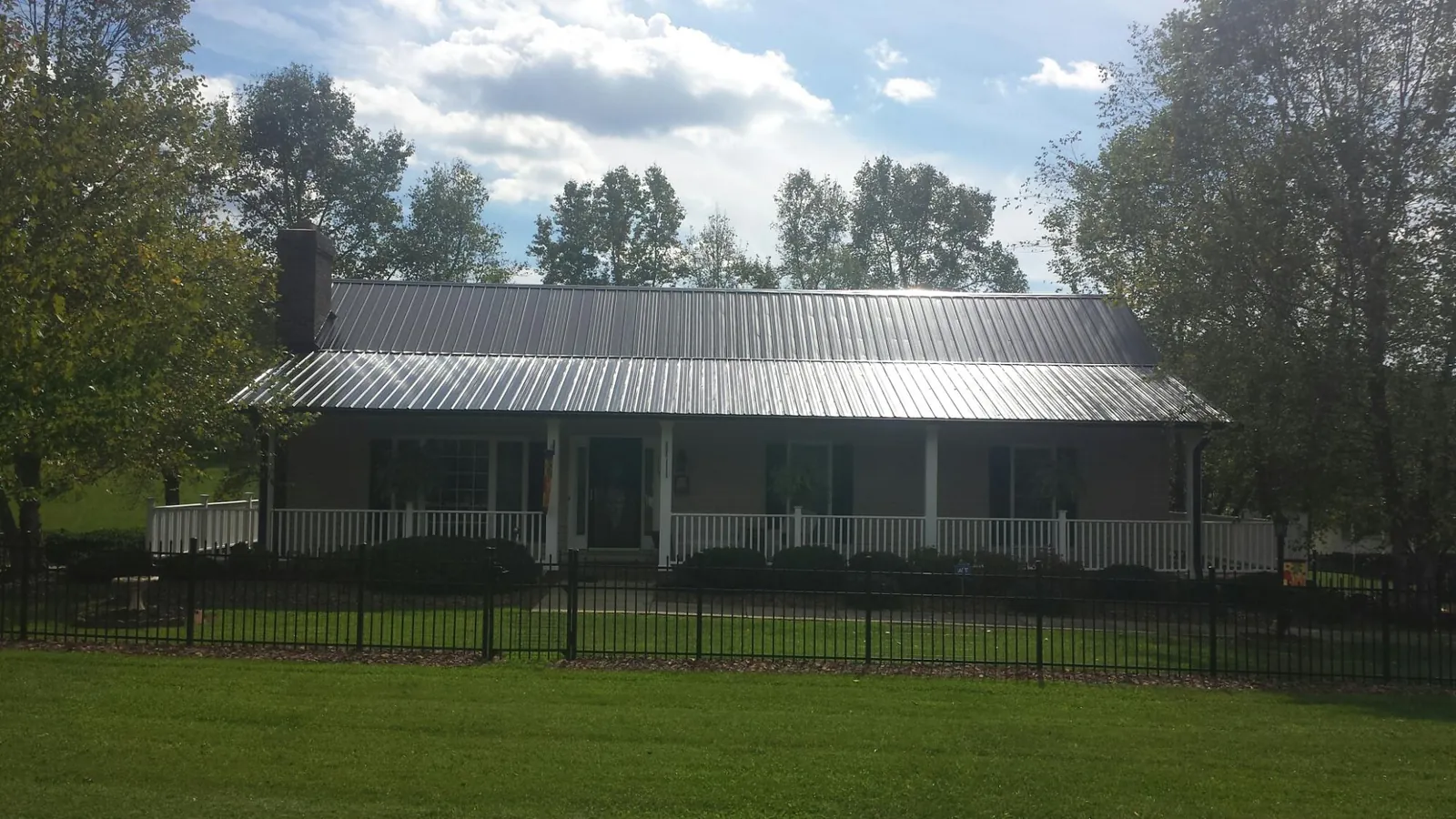 Gray metal roof on a brick ranch with a full width front porch — Gutter Guard Installation work by our crew in Bloomsbury