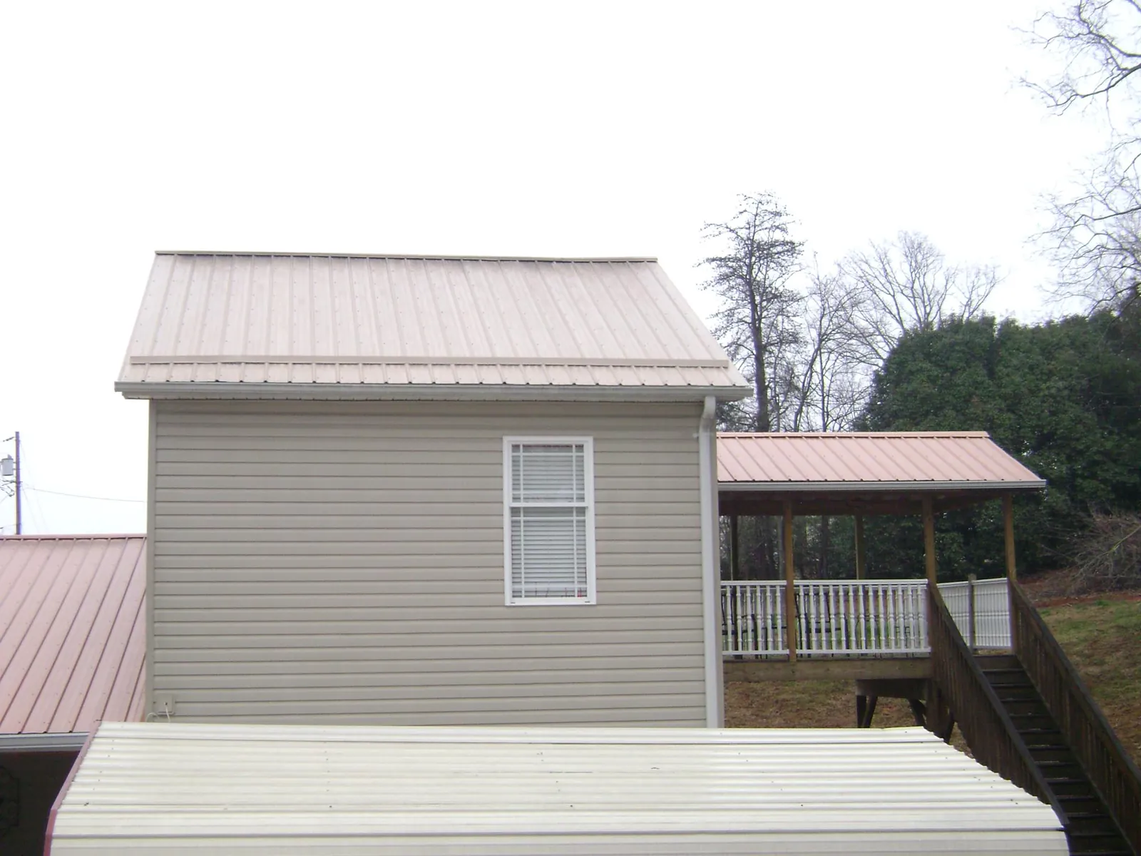 Tan metal roofs on a two story addition and attached porch, from a Roof Replacement job in Bloomsbury