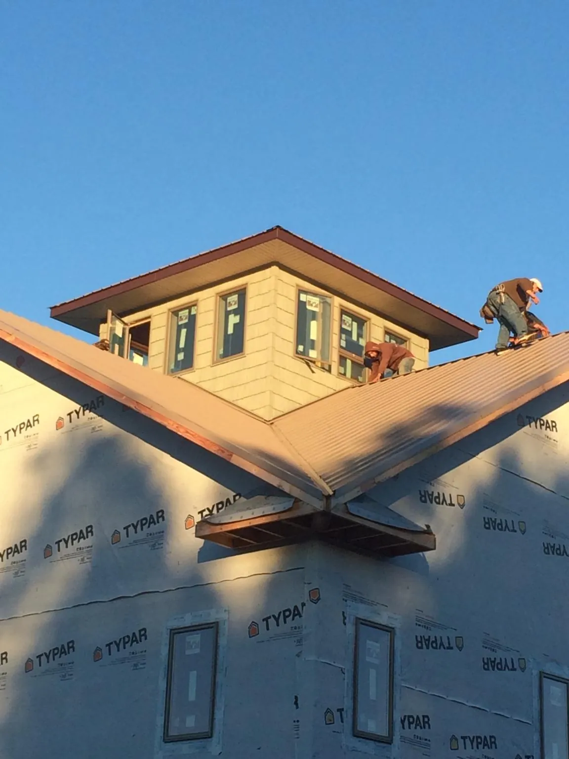 Roofers working around a rooftop cupola on a new metal roof at sunset — Roof Waterproofing in Bloomsbury by Roofing Brothers